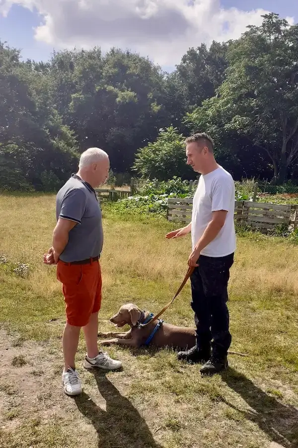 Deux hommes discutent pendant un cours d'éducation canine près de Rouen. L'un d'eux tient un chien en laisse.
